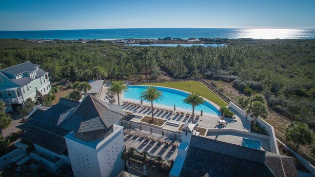 Un resort con una piscina grande, varias zonas de descanso y vista al océano.