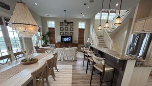 Amplia sala de estar con mesa de comedor, sillas y una isla de cocina.