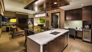 A modern kitchen with a central island, built-in appliances, and a dining area with a view of the cityscape.