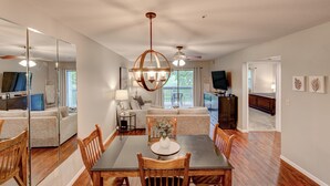 A modern living room with a dining area, a large mirror, and a ceiling fan.