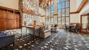 A spacious living area with a stone wall, wooden furniture, and large windows offering a view of the outdoors.