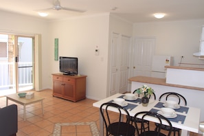 Enjoy meals in this well-equipped kitchen and dining area, featuring a TV, dining table, and outdoor access.