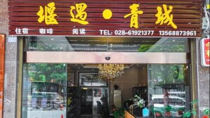 A hotel entrance with a wooden facade, glass doors, and potted plants. - Yan Yu Qing Cheng Inn (Chengdu)