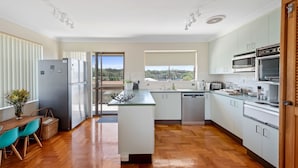 A modern kitchen with a central island, white cabinetry, and a view of the outdoors.