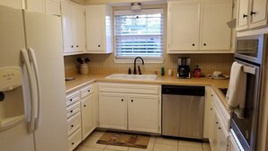 A kitchen with white cabinets, a dishwasher, a coffee maker, and a refrigerator.