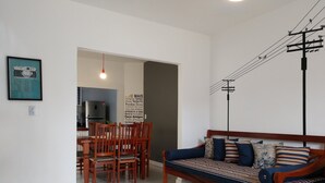 Una sala de estar con sofá, sillas, una mesa de comedor y una cocina al fondo.