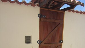 Una puerta de madera con bisagras metálicas y suelo de baldosas.