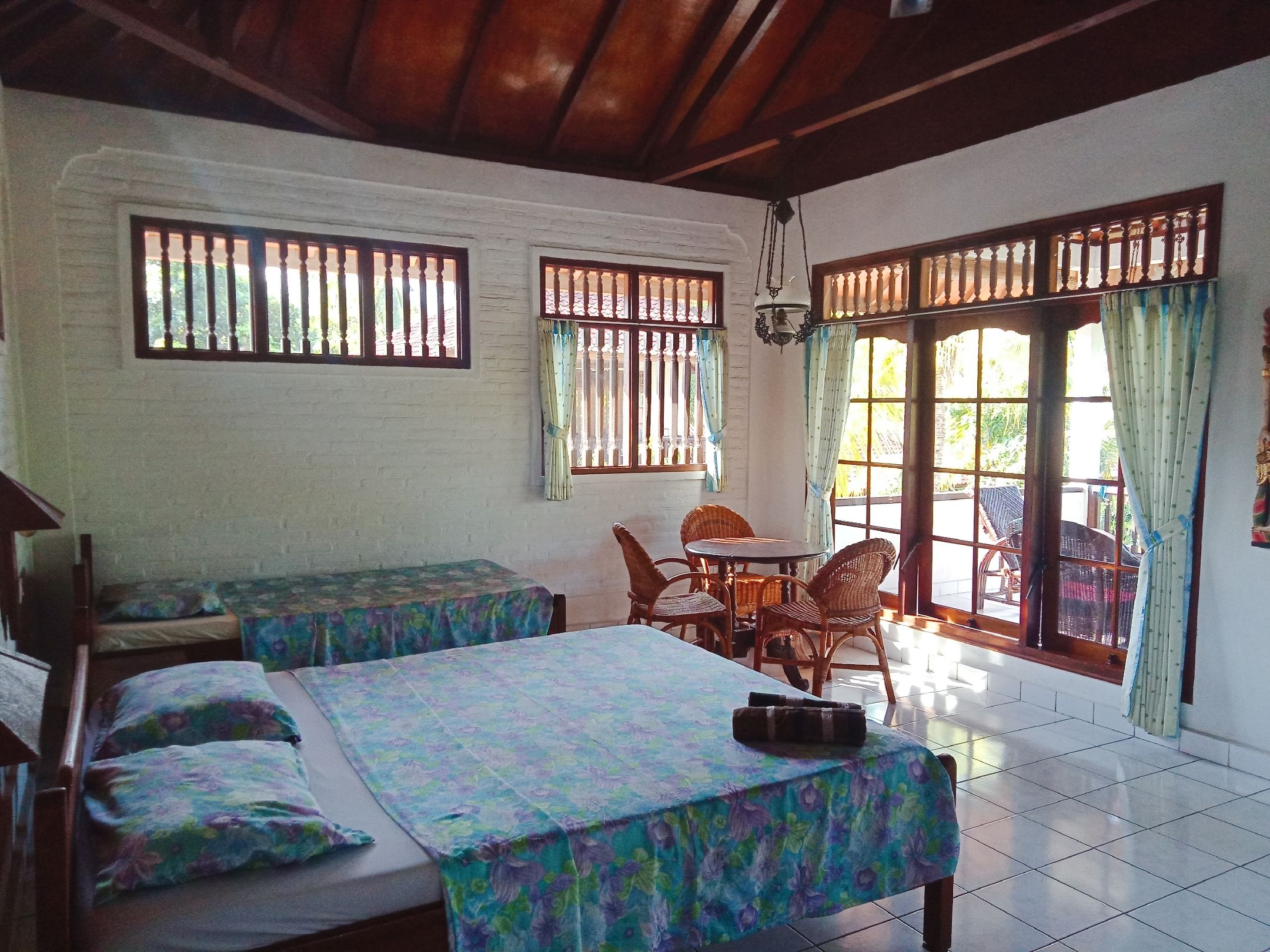 Una habitación con cama, una mesa y sillas, ventanas y vistas al exterior.