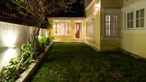 Un cortile ben illuminato con un piccolo edificio, una recinzione bianca e alcune piante.