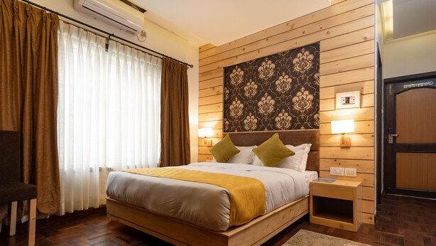 Un letto con struttura in legno, una coperta bianca e gialla, due abat-jour e un arazzo decorativo al muro.