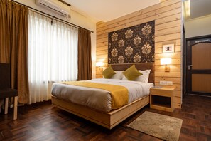 A wooden-framed bed with a white and yellow bedspread, two bedside lamps, and a patterned wall hanging. - Fresco Retreat (Lalitpur)