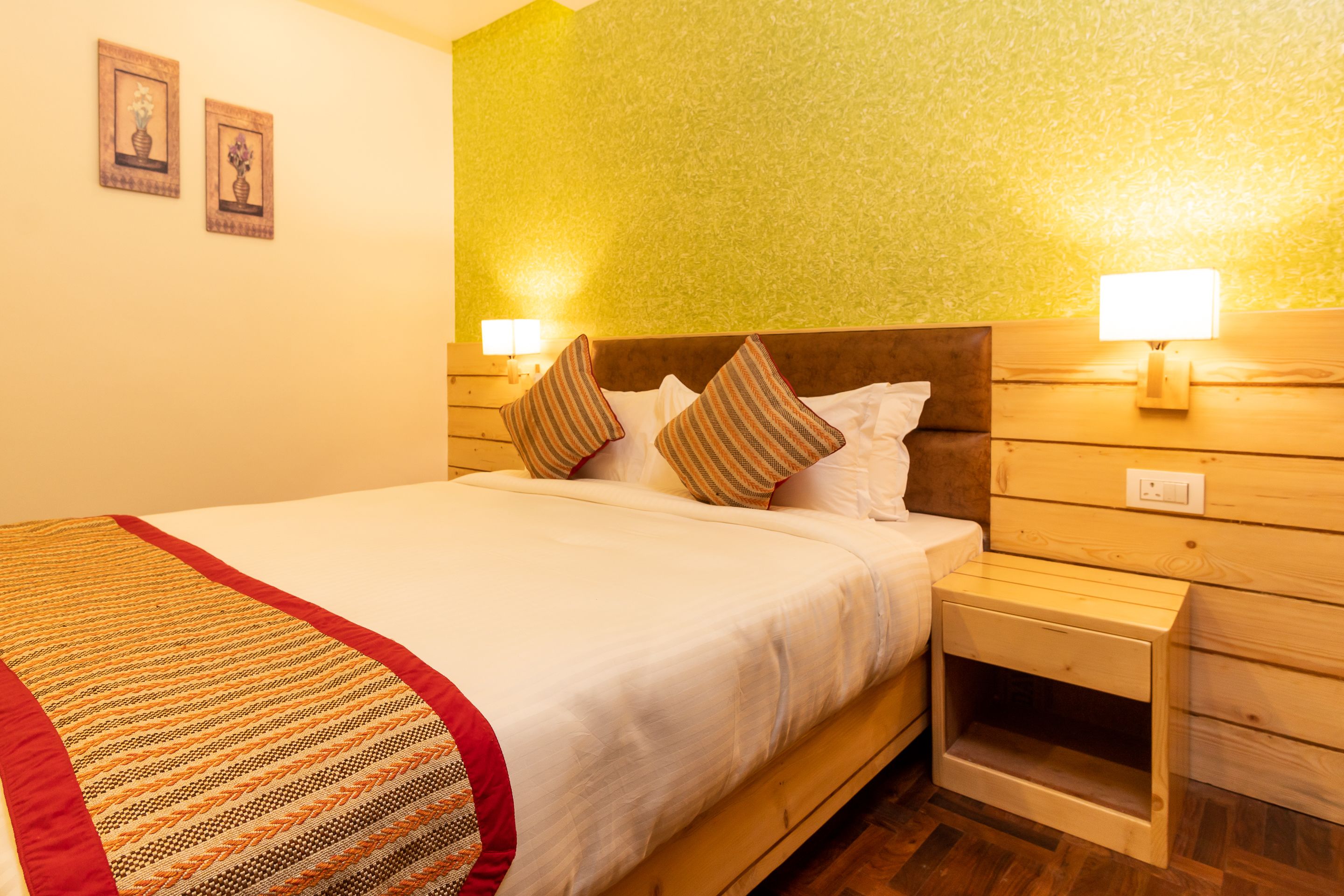 A neatly made bed with a striped blanket, wooden headboard, and two bedside lamps.