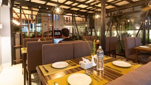 Un ristorante con tavoli in legno e sedute imbottite, completo di posate e bottiglie d'acqua.