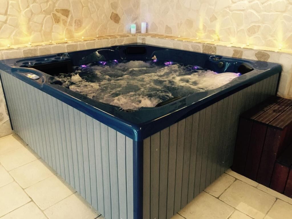 Un jacuzzi con pared de piedra y piso de baldosas.