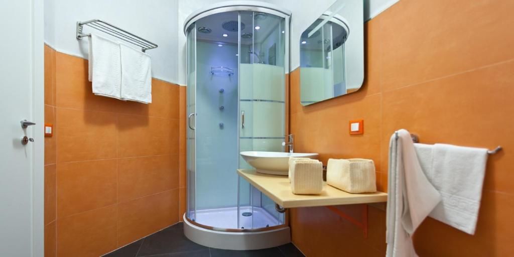 A modern bathroom with a glass-enclosed shower, a sink, and a mirror.