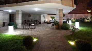 Ein Terrassenbereich im Freien mit Steinböden, Sitzgelegenheiten und Topfpflanzen.