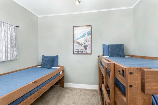 Un dormitorio con dos literas de madera, un colchón azul y un cartel en la pared.