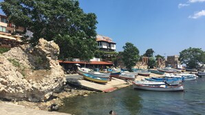 Une zone riveraine où sont amarrés des bateaux, avec des murs en pierre et des bâtiments portant des enseignes, dont certaines indiquent « RESTAURANT ».