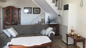 Un salon comprenant un canapé, une table basse, un meuble et un escalier.