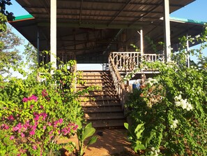 A covered outdoor staircase with a metal railing, surrounded by lush greenery and flowering plants. - Vongkham Eco Resort (Dongmakkhai)