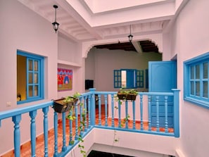 A multi-level interior with a blue railing, a tiled floor, and a ceiling with exposed beams.