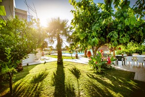 Um jardim bem cuidado com piscina, palmeiras e área de estar externa.