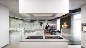 Una cocina moderna con una isla central, una persona al fondo y un letrero de neón en la pared.