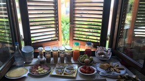 A breakfast buffet with various food items and condiments on a table near a window with blinds. - L' Antico Borgo (Milazzo)