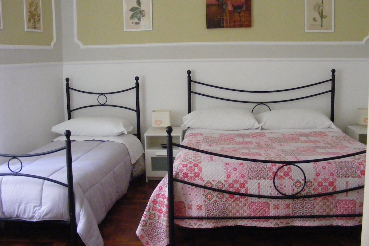Two twin beds with white bedding and a floral quilt on the larger bed.
