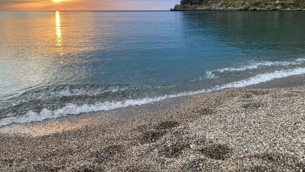A beach with pebbles, calm water, and a rocky cliff. - L' Antico Borgo (Milazzo)