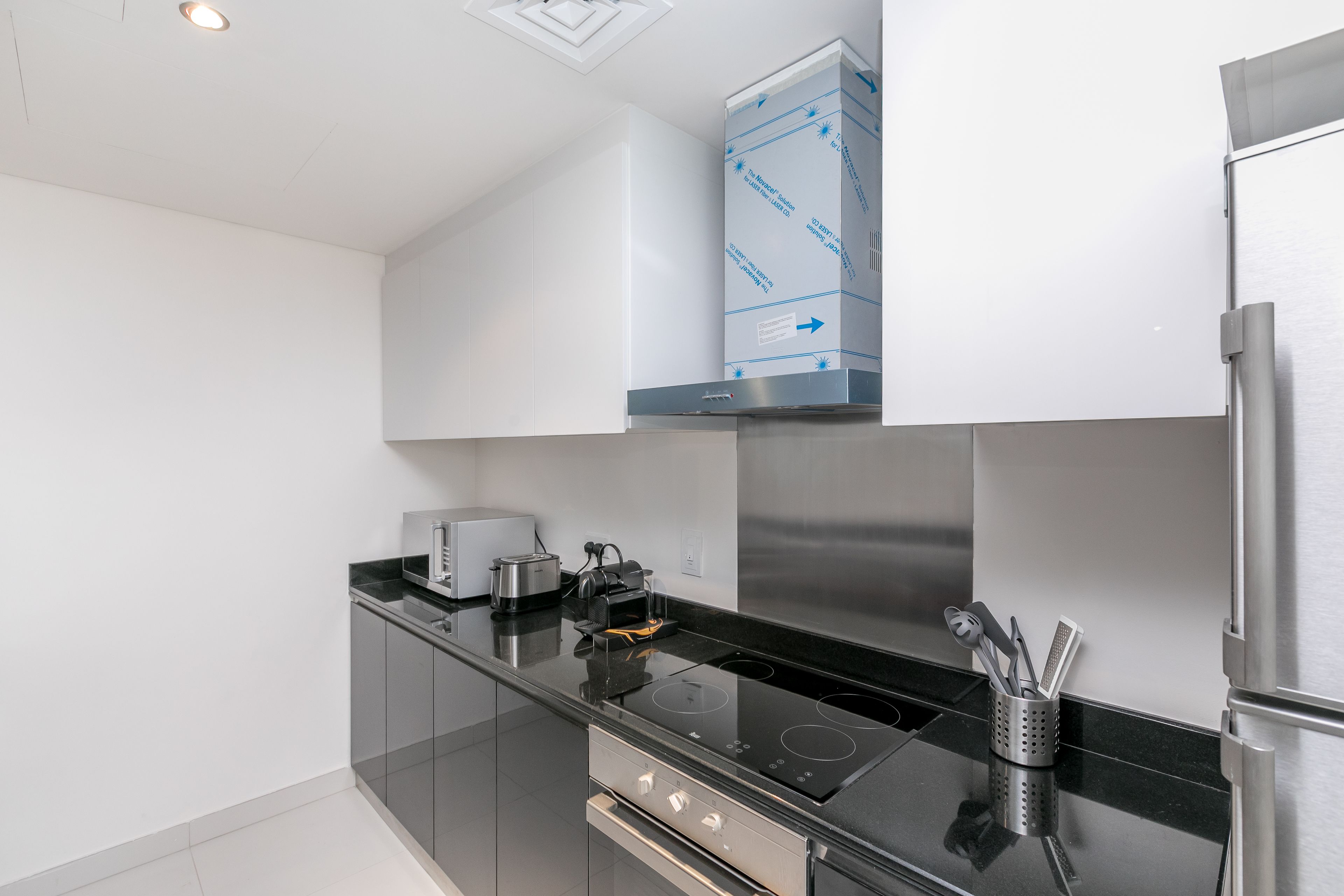 A modern kitchen with a black countertop, stainless steel appliances, and a built-in oven.
