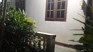 A dimly lit staircase leading to a room with a window, surrounded by greenery. - Vijitporn House Hotel (Mae Hong Son)