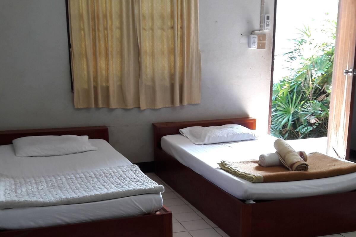 A hotel room with two beds, a curtain, a window, and a door leading to a balcony.