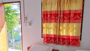 A hotel room with two beds, a window with a view of greenery, and a curtain with a red and gold pattern. - Vijitporn House Hotel (Mae Hong Son)