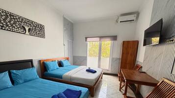 A hotel room with two beds, a wooden table, and a TV.