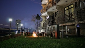 A building with a stone facade, outdoor seating, and a fire pit. - HBC Grand Himalayan Hotel & Resort (Kosiyakutoli)