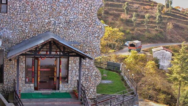 A stone building with a wooden porch and a staircase leading to the entrance. - HBC Grand Himalayan Hotel & Resort (Kosiyakutoli)