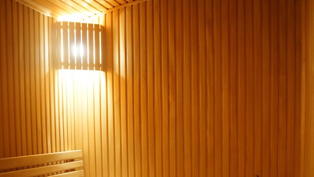 Un sauna avec des bancs en bois, une petite table avec des serviettes et un seau avec une louche.