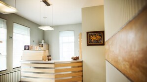 Un comptoir d’accueil avec un revêtement en bois, une œuvre d’art encadrée au mur et une fenêtre avec des stores.