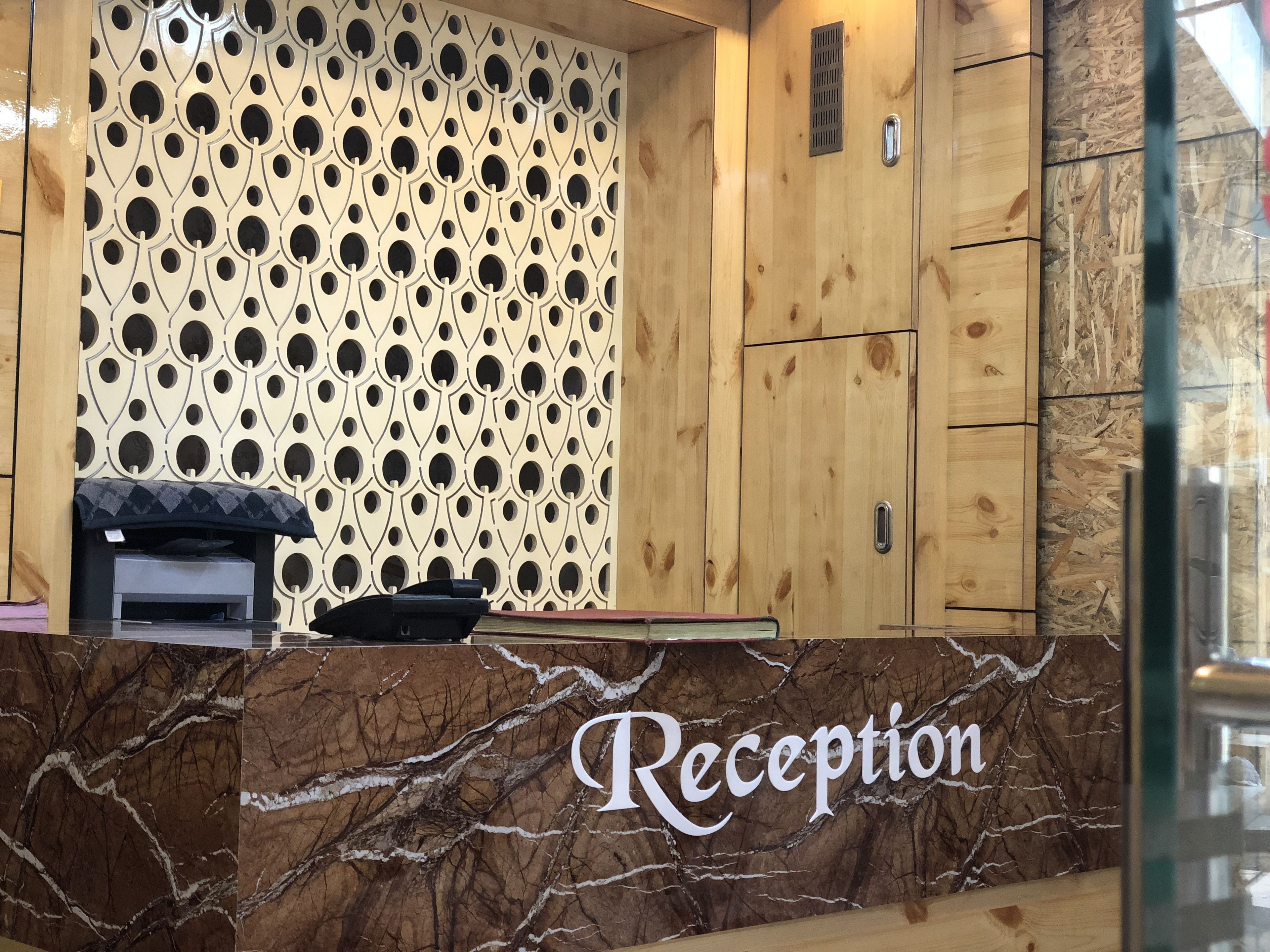 Una recepción con encimera de mármol y un papel tapiz decorativo al fondo.