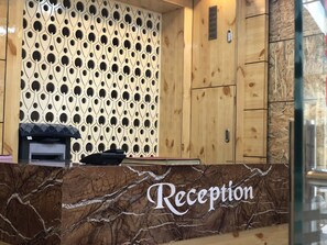 A reception desk with a marble top and a patterned wall behind it. - Hotel Bani Hashim (Ajmer)