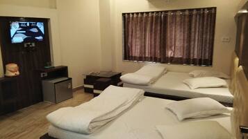 Habitación de hotel con dos camas, televisión, un escritorio pequeño y ventana con cortinas.