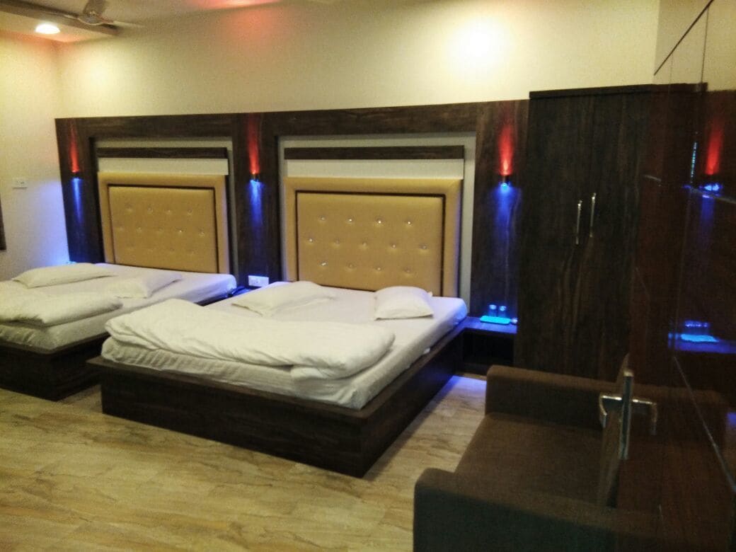 Quarto de hotel com duas camas, um guarda-roupa e uma pequena mesa.