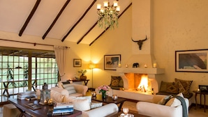 A cozy living room with a fireplace, comfortable seating, and a chandelier. - Kili Villa (Arusha)