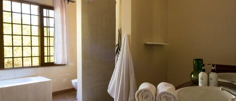A bathroom with a bathtub, a shower, a sink, and a window with a view of trees.