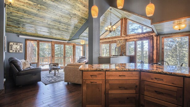 Un amplio espacio habitable con una gran mesa de comedor de madera, un sofá y una cocina con armarios de madera y encimera de granito.