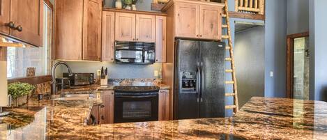 A kitchen with wooden cabinets, a stainless steel refrigerator, a microwave, and a stove.