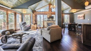 Amplia sala de estar con chimenea, asientos cómodos y comedor con gran ventanal que da a una terraza.