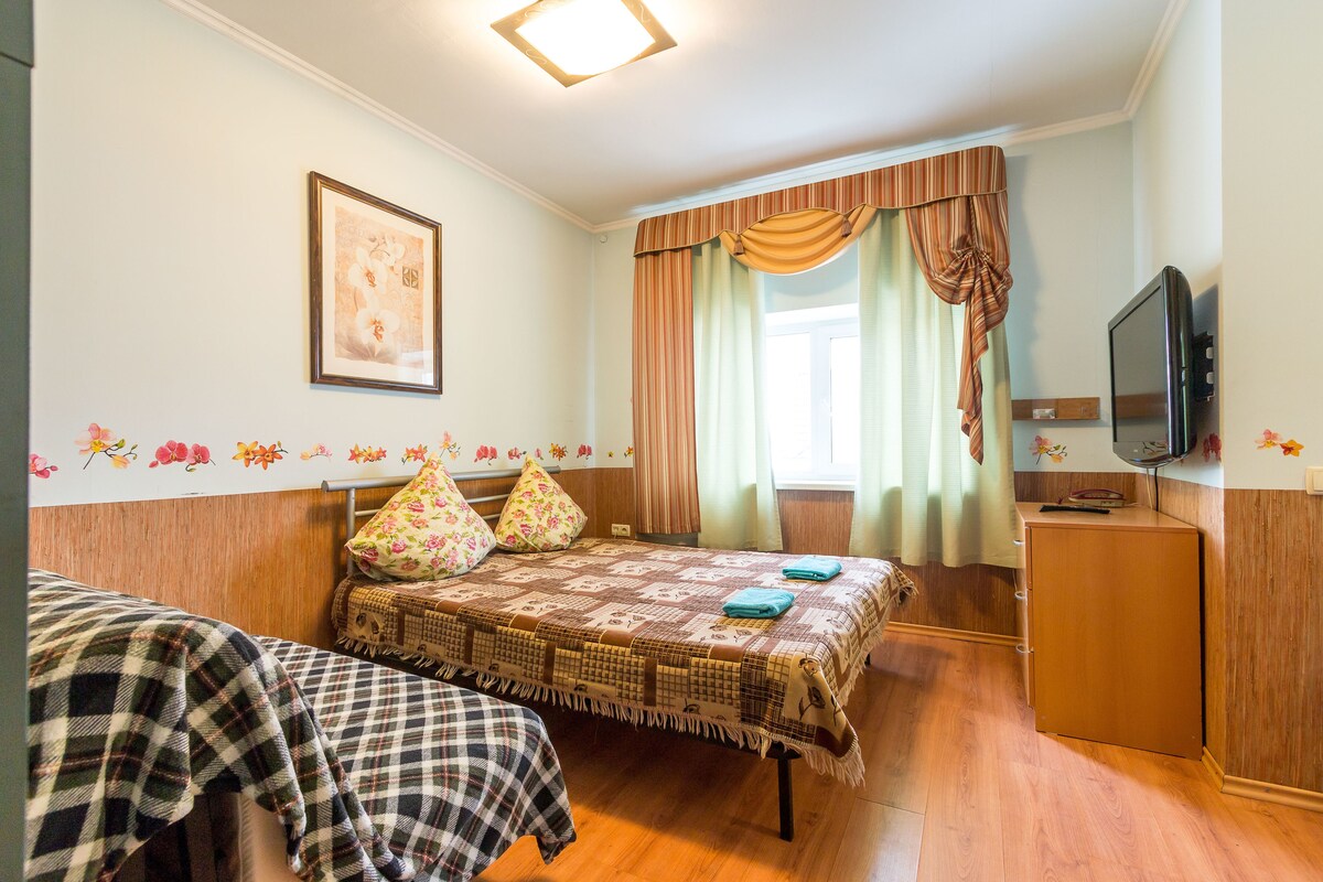Une chambre avec deux lits, une télévision et une fenêtre avec des rideaux.