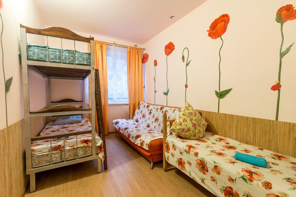 Une pièce comprenant un lit superposé, un canapé et un mur décoré de motifs floraux.
